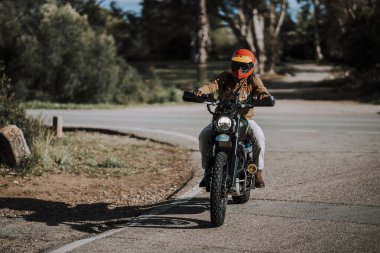 Genç adam yolda motosiklet sürüyor..