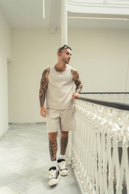 Yakışıklı, dövmeli, şık elbiseli bir adamın uzun bir portresi.