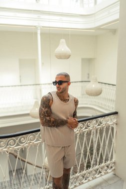 Beyaz güneş gözlüklü genç adam içeride dikiliyor..