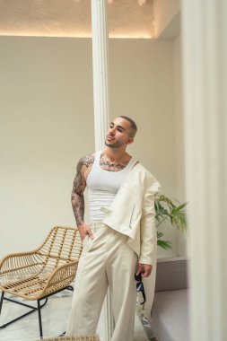 Beyaz takım elbiseli yakışıklı bir genç ve yüzünde bir gülümseme olan beyaz bir gömlek.