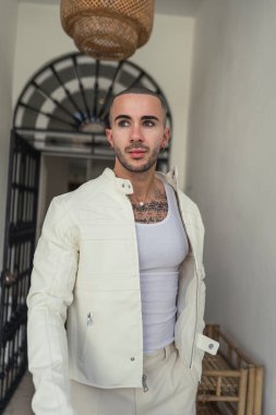 Beyaz gömlekli yakışıklı bir genç adam portresi ve iç mekânda poz veren şık bir vücut..