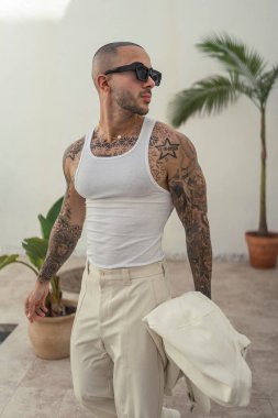 Dövmeli genç adam şehirde poz veriyor.