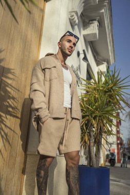 Yakışıklı, kahverengi sakallı, şık görünümlü, modaya uygun kıyafetler giyen, modern binanın yanında duran, kameraya bakan,