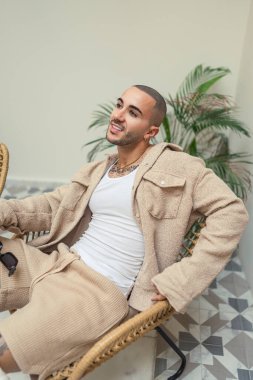 Kahverengi saçlı yakışıklı genç adam sandalyede oturuyor..