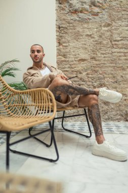 Genç sakallı adam bir sandalyede evde rahatlatıcı