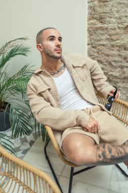 Genç adam kanepede oturuyor ve kahve içiyor.