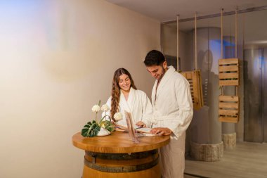 Bornozlu genç çift rahatlıyor ve kaplıcaların tadını çıkarıyor.