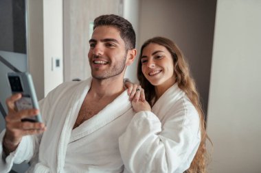 Otellerinde bornoz giyen genç bir çift.