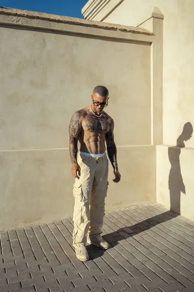 Beyaz bluz giyen ve binanın önünde poz veren genç, yakışıklı bir adam..