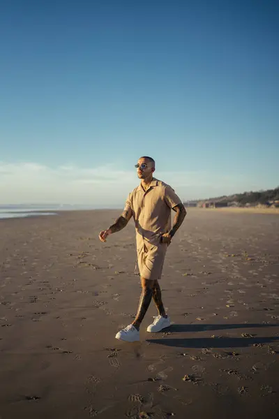 Kıdemli adam kumsalda elleri kenarda yürüyor.