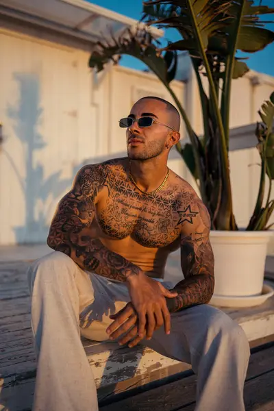 Parktaki bankta oturan güneş gözlüklü yakışıklı bir gencin portresi.