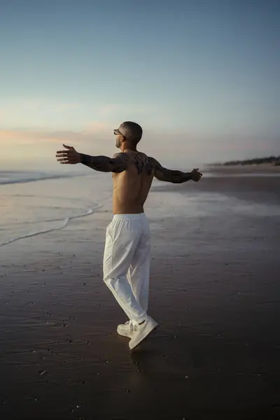 Sahilde kollarını açmış bir adam.