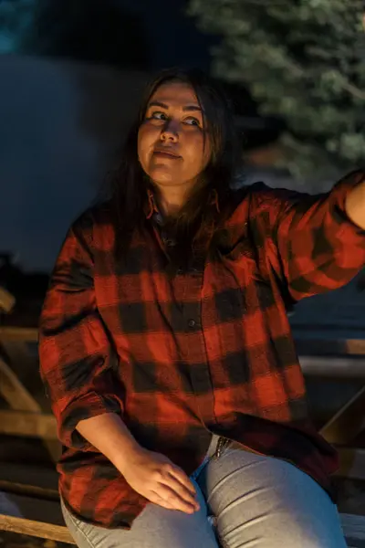 Ormanın arka planında bir bardak su ve sırt çantalı genç bir kadın.