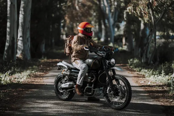 Yolda kask ve motosiklet takan genç bir adam.