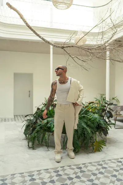 Beyaz tişörtlü, siyah şapkalı şık bir adam.