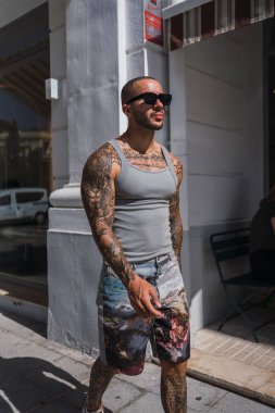 Güneş gözlüklü ve dövmeli yakışıklı bir adamın portresi.