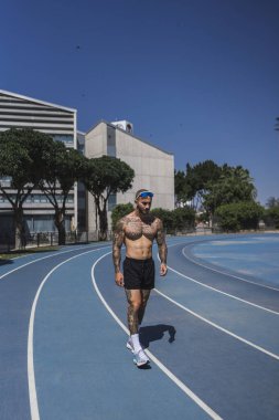 Genç adam stadyumda koşuyor..