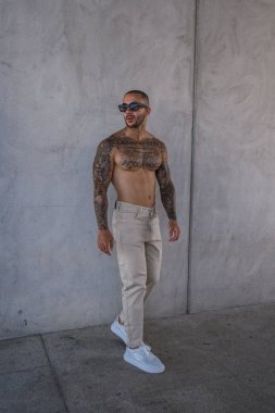 Beyaz güneş gözlüklü genç yakışıklı adam beton bir binanın önünde poz veriyor..