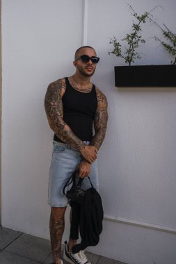 Siyah güneş gözlüğü takan dövmeli yakışıklı adam.