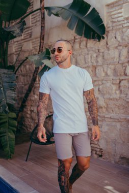 Dövmeli genç yakışıklı adam modern bir şehir parkında poz veriyor..