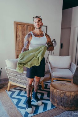 Modern bir odada dövmeleri olan genç bir adam..