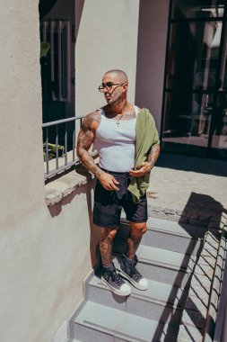 Merdivenlerde poz veren dövmeli bir adamın portresi.