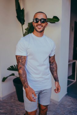 Dövmeli yakışıklı genç adam beyaz tişörtlü.
