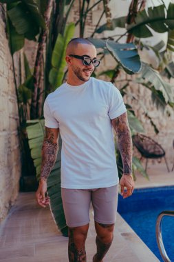 Dövmeleri dışarıda poz veren genç yakışıklı bir adam.