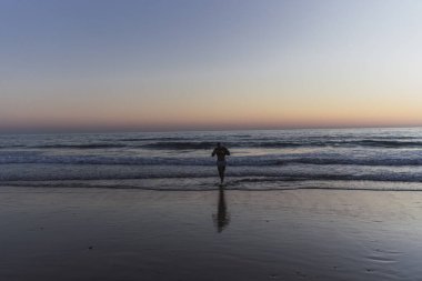 Gün batımında Sahilde Yürüyen Kadın
