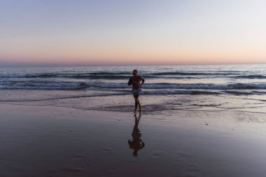 Gün batımında denizde koşan adam