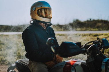 Klasik motosiklet kasklı adam yolda.