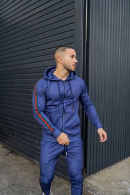 Spor giyimli genç yakışıklı adam kameraya poz veriyor.