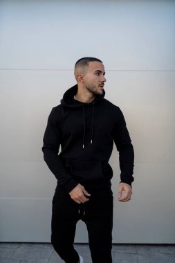 Siyah kapüşonlu beyaz kazaklı bir adam.