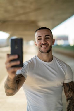 Sokakta dikilirken cep telefonunu kullanan yakışıklı bir adamın portresi.