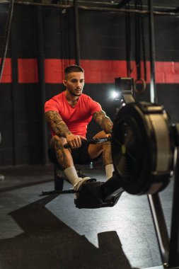 Genç adam spor salonunda ağır egzersizler yapıyor.