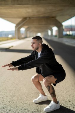 Spor giyimli genç yakışıklı sporcu sokakta egzersiz yapıyor..