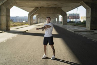 Genç adam yolda koşuyor ve geriniyor.