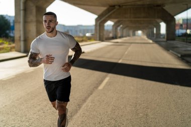 Spor kıyafetleri içinde koşan formda bir erkek.