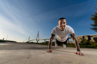 Yakışıklı adam sokakta esneme egzersizleri yapıyor.