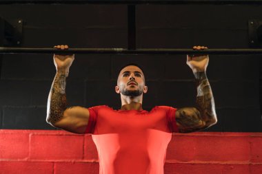 Genç kaslı adam spor salonunda egzersiz yapıyor.