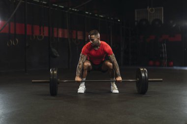 Genç kaslı adam spor salonunda halterle halter yapıyor..