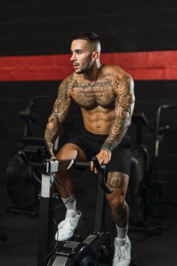 Yakışıklı kaslı adam spor salonunda makine üzerinde egzersiz yapıyor..