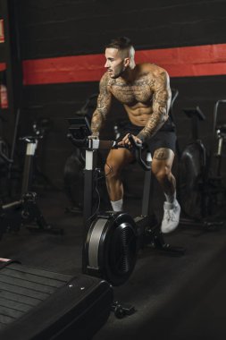 Spor salonunda halterle çalışan genç adam.