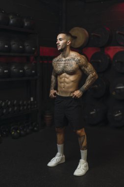 Spor salonunda halterli genç kaslı bir adam.