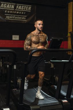 Koşu bandında egzersiz yapan genç adam.