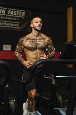 Spor salonunda kaslı vücudu ve göğsü olan bir adam.