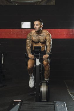 Genç adam makineye dönmek için ağır ağırlık egzersizi yapıyor.