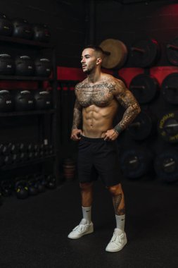 Spor salonunda dövmeli kaslı bir adam.