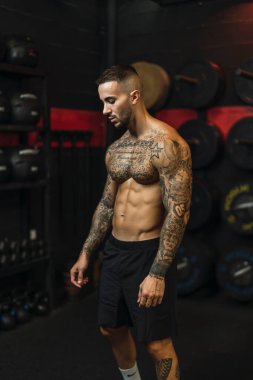 Yakışıklı kaslı adam spor salonunda ağır ağırlık egzersizi yapıyor.