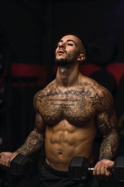 Spor salonunda spor yapan üstsüz genç adam.